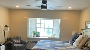 A bedroom with a bed, a chair, a window with blinds, a ceiling fan, and a lamp. - Peaceful/Spacious Downtown home Branson near Lake Taneycomo w/great amenities   (Branson)