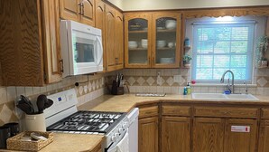 A kitchen with wooden cabinets, a microwave, a stove, and a sink. - Peaceful/Spacious Downtown home Branson near Lake Taneycomo w/great amenities   (Branson)