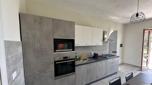 A modern kitchen with grey cabinets, a built-in microwave, and a gas stove. - 3 Bedroom Apartment in Santa Maria (Santa Maria)