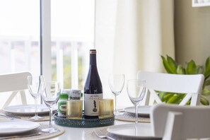 A dining table set with plates, glasses, a bottle of wine, and a small decorative item.