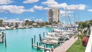 A marina with boats docked, a tall building in the background, and a clear blue sky.