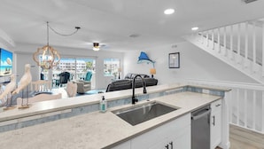 A modern kitchen with a central island, a built-in dishwasher, and a view to the outside.