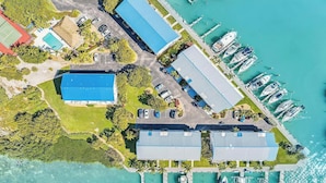 An aerial view of a marina with boats docked, a tennis court, and a building with a blue roof.
