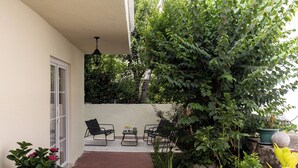 Eine Terrasse mit zwei Stühlen und einem Tisch, umgeben von Pflanzen und einer Mauer.