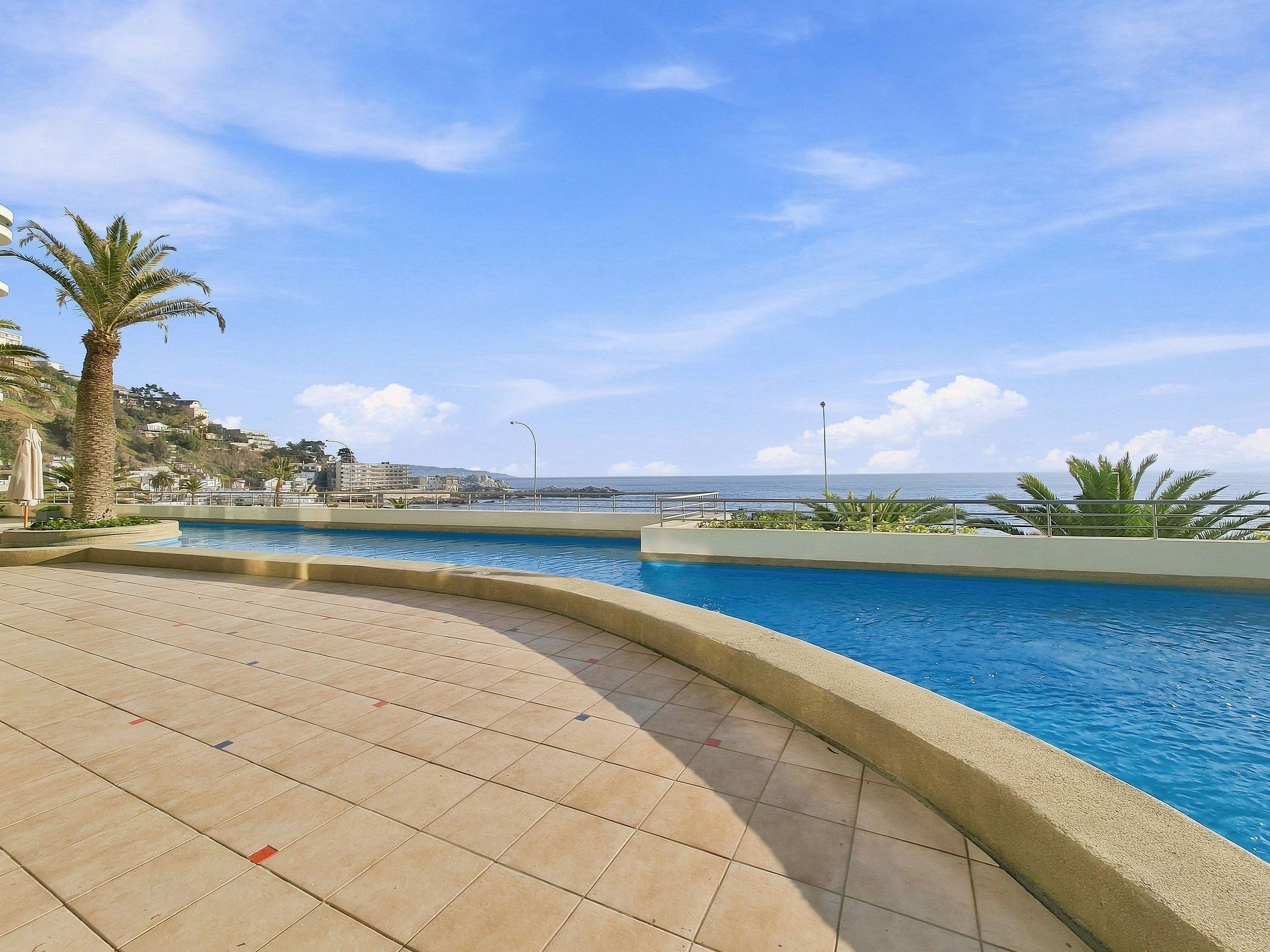 A swimming pool with a curved edge, surrounded by a tiled deck.