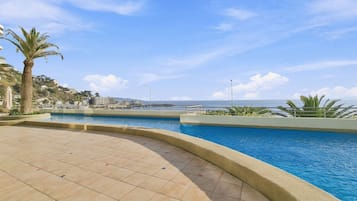 A swimming pool with a curved edge, surrounded by a tiled deck.