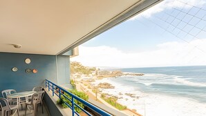 A balcony with a view of the ocean, a table with chairs, and a railing. - Oceana Suites EuroVista (Vina del Mar)