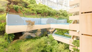 A modern bridge connecting two buildings with a lush green landscape below. - Oceana Suites EuroVista (Vina del Mar)