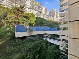 Un edificio residencial de varios niveles con balcones, rodeado de abundante vegetación.