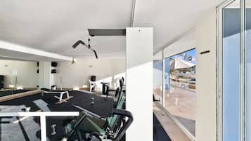 A gym with exercise equipment, a large mirror, and a view of the outside.