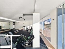 Un gimnasio con equipo de ejercicio, un espejo grande y vistas al exterior.