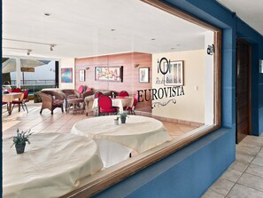 Un restaurante con vistas al mar, con mobiliario de mimbre y un letrero que dice 'EUROVISTA Resto-Bar'.