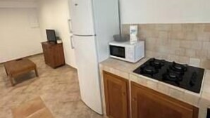Eine kompakte Küche mit Kühlschrank, Mikrowelle, Herd und Holzschränken.