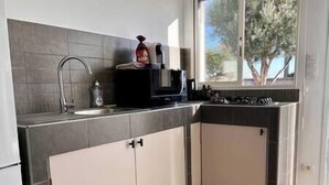 A modern kitchen with a sink, stove, and cabinets. - Appartement Laranceto vue mer Avec Piscine (Biguglia)