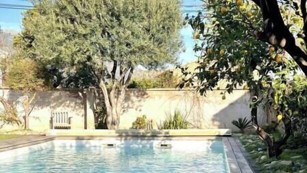A swimming pool with clear water, surrounded by trees and a stone wall. - Appartement Laranceto vue mer Avec Piscine (Biguglia)