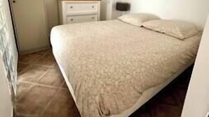 A bedroom with a bed, a nightstand, a dresser, and a door. - Appartement Laranceto vue mer Avec Piscine (Biguglia)