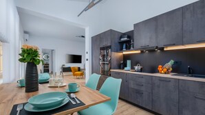 Une cuisine moderne avec des meubles de couleur sombre, une table à manger en bois et des chaises turquoise.
