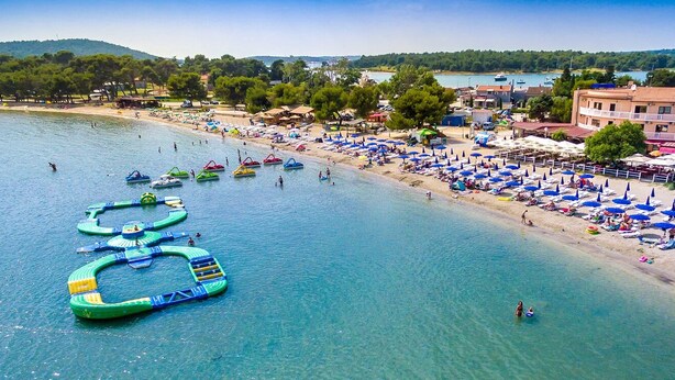 Ein Hotel an der Küste mit Annehmlichkeiten direkt am Strand, darunter Sonnenschirme und Liegestühle.