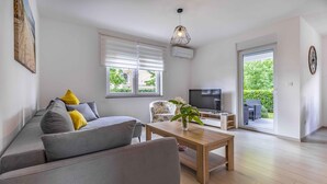 Ein modernes Wohnzimmer mit einem grauen Sofa, einem Holztisch und einem Fernseher.