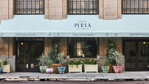 The exterior of Hotel Perla, Los Angeles, featuring a restaurant and bar, rooftop cocktail area, and potted plants along the sidewalk. - Hotel Per La (Los Angeles)