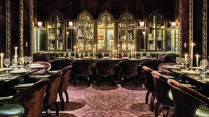 A formal dining room with a long table set for multiple guests, flanked by tall, ornate mirrors and candle-lit walls. - Hotel Per La (Los Angeles)