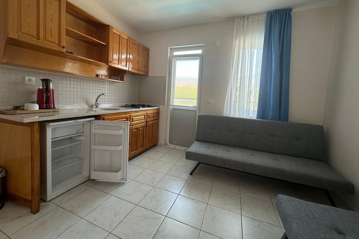 Eine kleine Küche mit Holzausstattung, einem eingebauten Backofen und einem grauen Sofa.