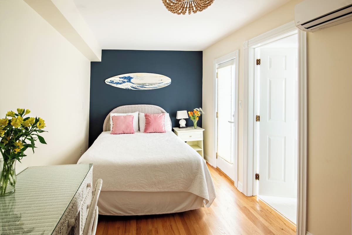 A bedroom with a bed, bedside table, and a wall-mounted artwork.