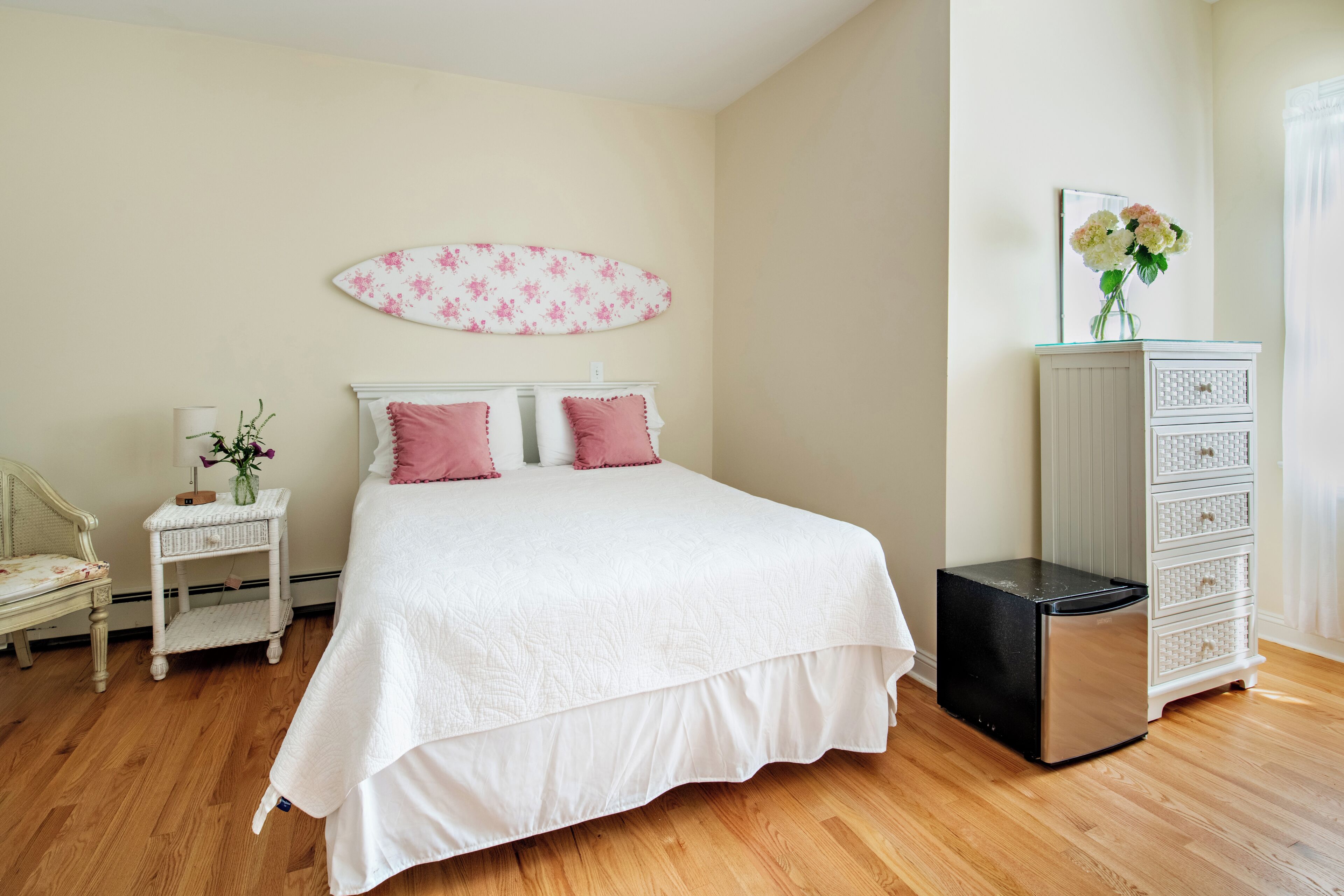 Un dormitorio con cama, mesita de noche, cómoda y una decoración de tabla de surf en la pared.