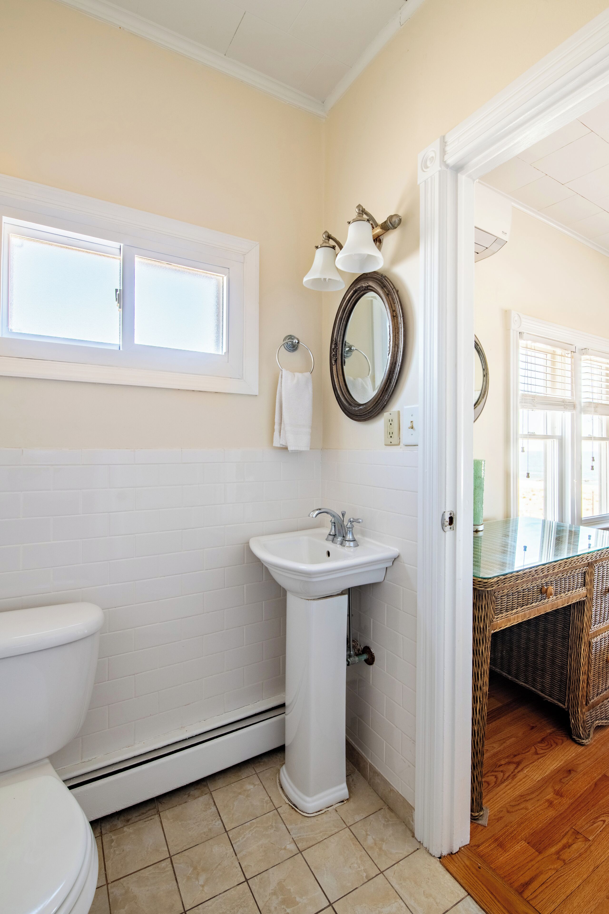 A bathroom with a toilet, sink, and mirror.