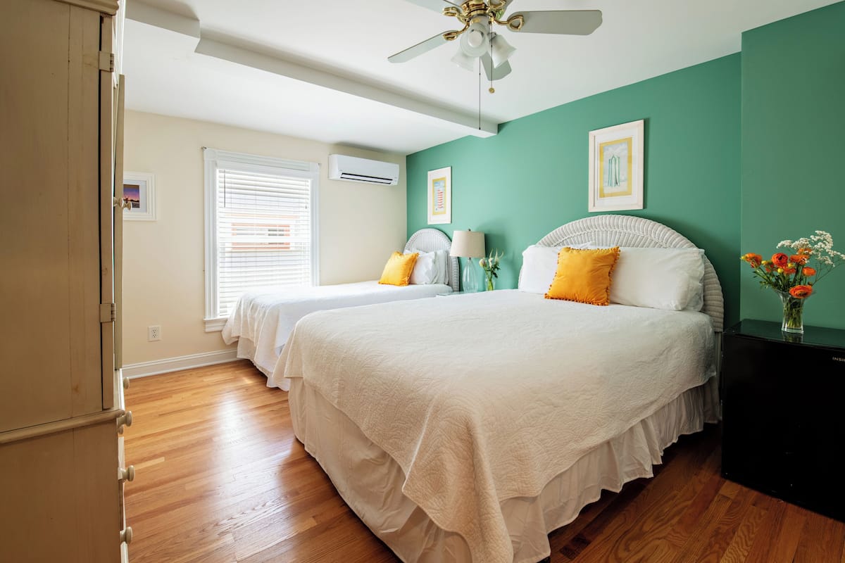 A bedroom with two beds, a ceiling fan, and a window with blinds.