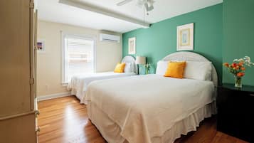 A bedroom with two beds, a ceiling fan, and a window with blinds.