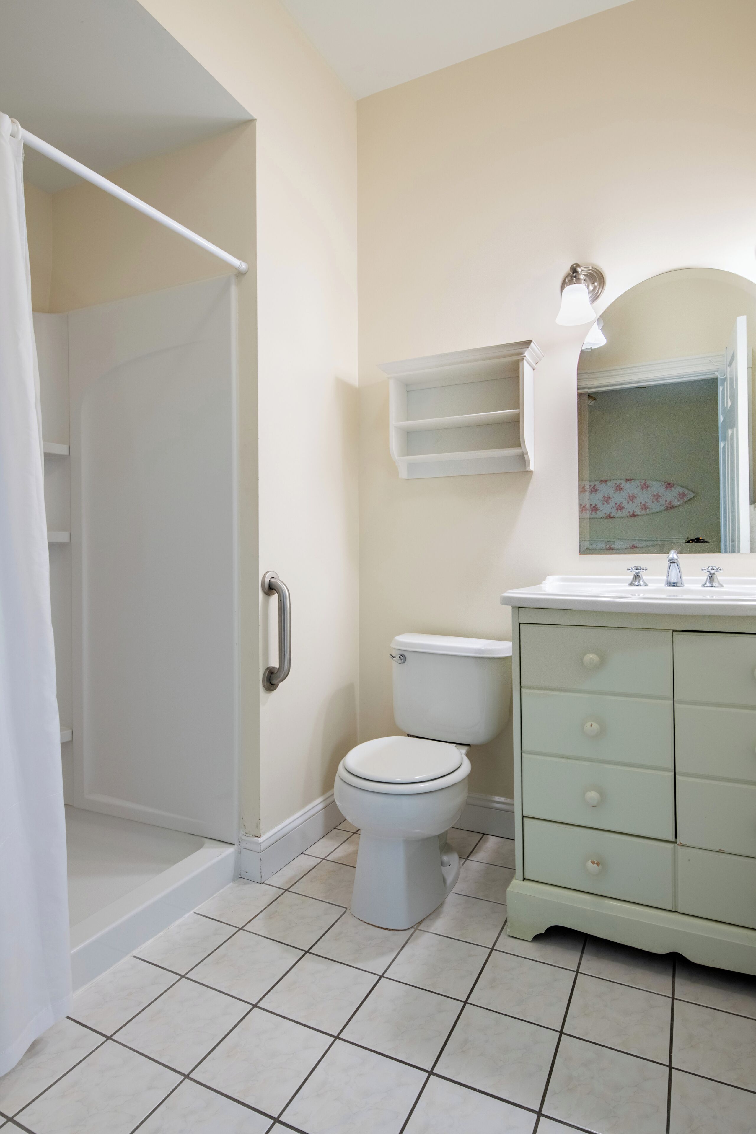 Un baño con ducha, inodoro y tocador con cajones.