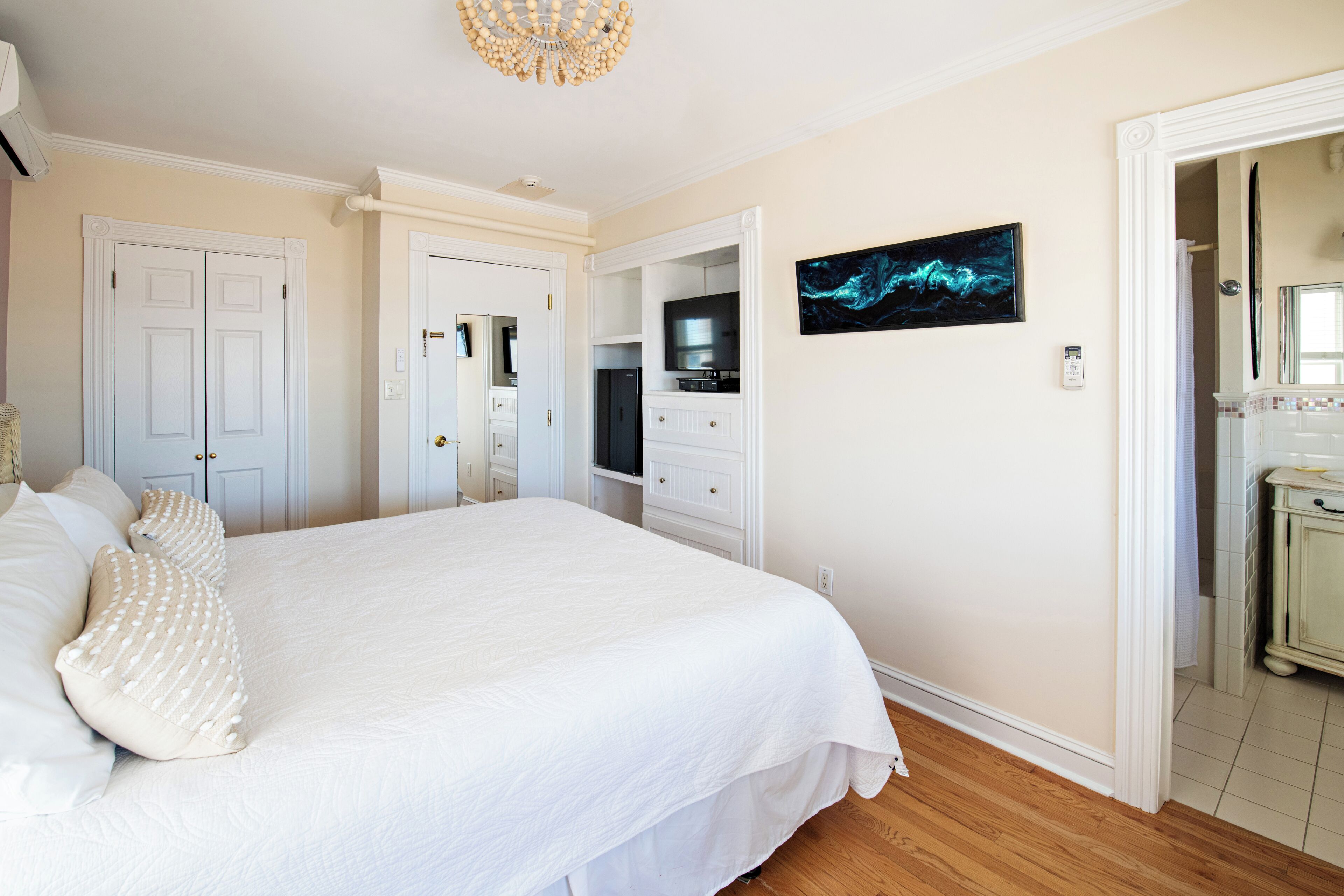 Ein Schlafzimmer mit einem großen Bett, einem Fernseher, einem Spiegel und einer Tür zu einem Badezimmer.