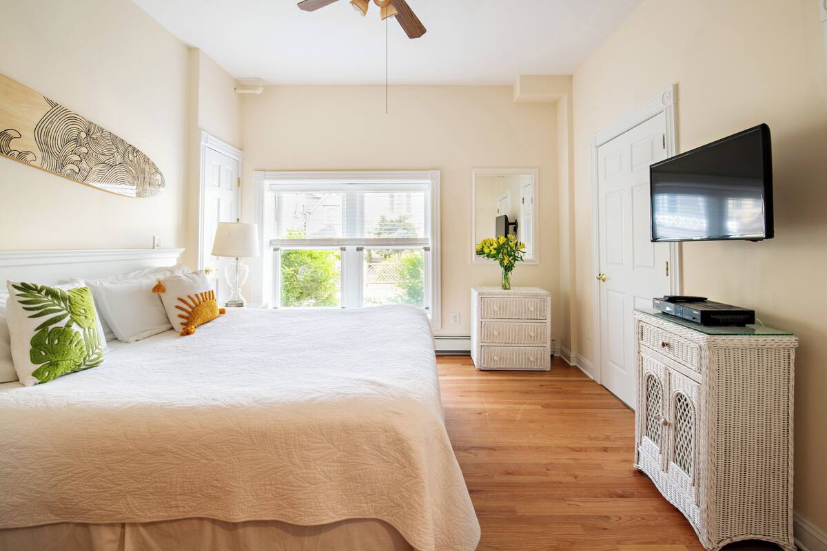 A bedroom with a bed, a television, a dresser, and a window.