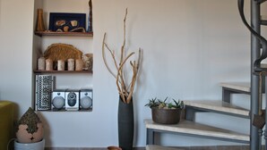 A staircase with a modern design, a wall-mounted shelf with decorative items, and a potted plant.