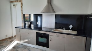 A modern kitchen with a black countertop, stainless steel appliances, and a tiled backsplash.