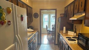 Une cuisine avec des meubles de rangement en bois, un réfrigérateur, une cuisinière et un four à micro-ondes.