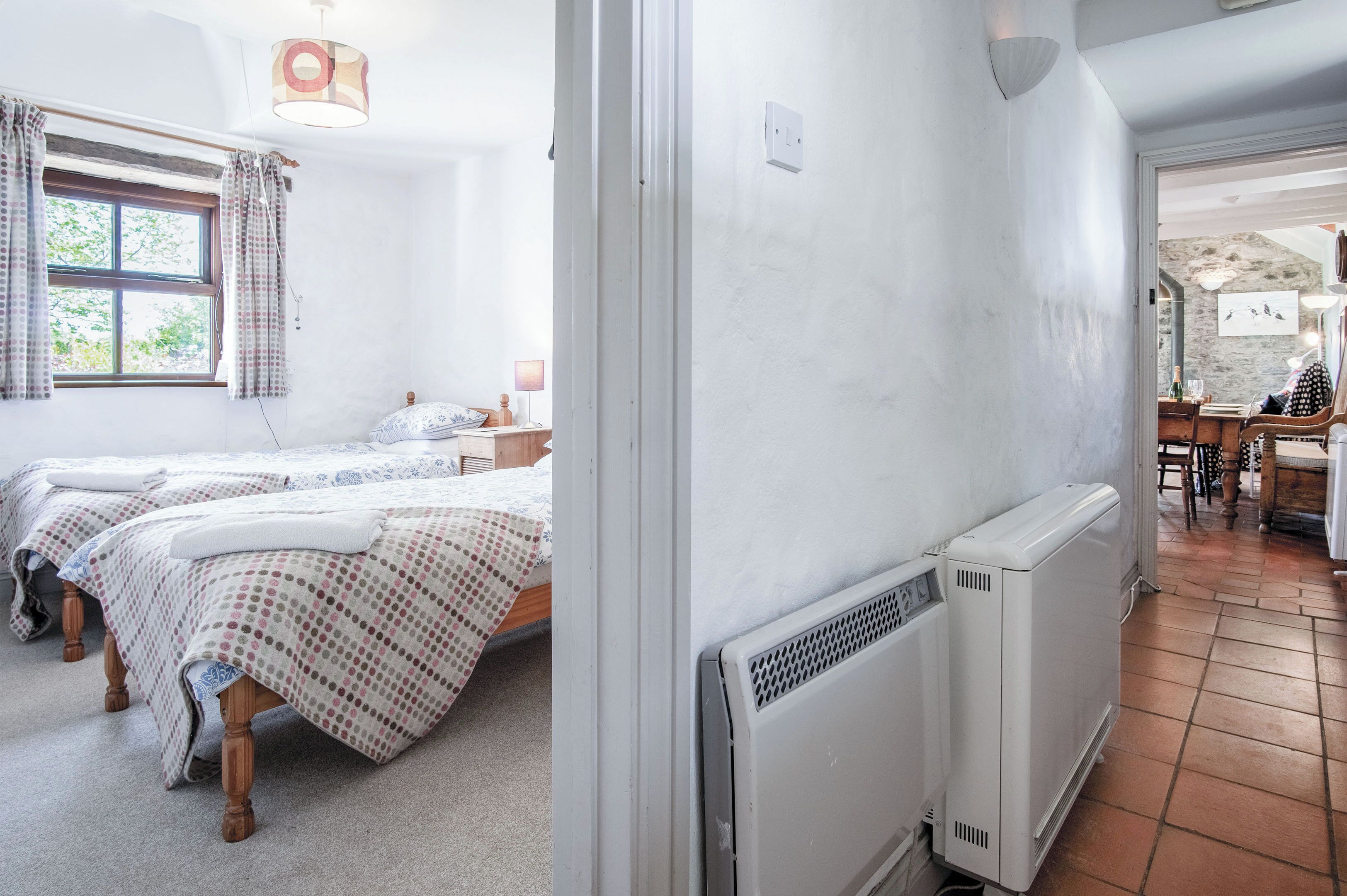 A room with two beds, a radiator, and a window with curtains.