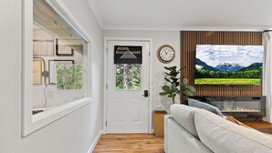 Una sala moderna con chimenea, un televisor montado en una pared de madera y una puerta con vistas a una ventana.