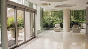 Un'ampia hall con ingresso in vetro, arredi moderni e vista sul verde circostante.