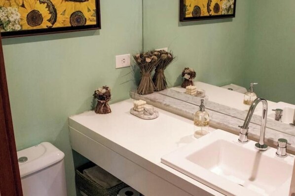 A bathroom with a white sink, a mirror, and decorative items including dried flowers and a soap dish.