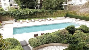 Una piscina rettangolare con lettini e un solarium in pietra che la circonda.