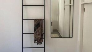 Un dormitorio con cama, una escalera fijada a la pared, un espejo y un armario.