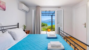 Una camera da letto con un letto, una pianta in vaso e vista su un balcone con tavolo e sedie.