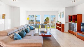 A spacious living room with a beige sofa, a dining table, and a TV stand. - Villa Costa Adeje by Villa Plus (Adeje)