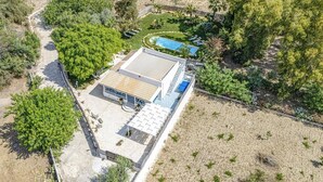 Eine Vogelperspektive auf ein modernes Haus mit Schwimmbad, umgeben von Grünflächen und einer Wüstenlandschaft.