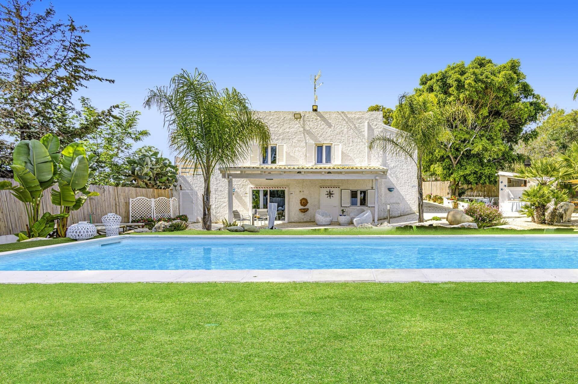 Una casa de dos pisos con una piscina delantera.