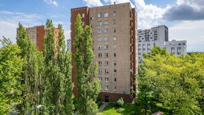 A multi-story residential building with a flat roof, surrounded by lush green trees. - Kraków Czyżyny - Terrace & Workspace - by Rentujemy (Kraków)