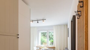 A modern living room with a dining area, wooden flooring, and a large window with curtains. - Kraków Czyżyny - Terrace & Workspace - by Rentujemy (Kraków)