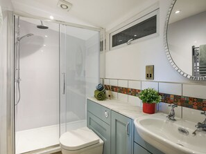 Ein Badezimmer mit Duschkabine, Toilette, Waschbecken und Spiegel.